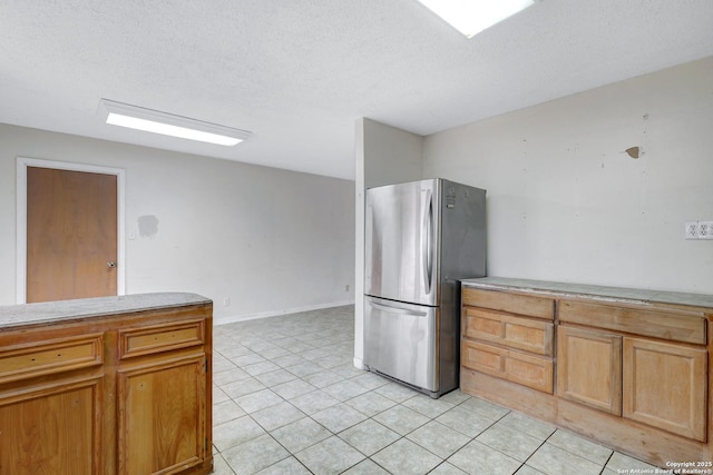 kitchen with light tile patterned floors, light countertops, a textured ceiling, and freestanding refrigerator