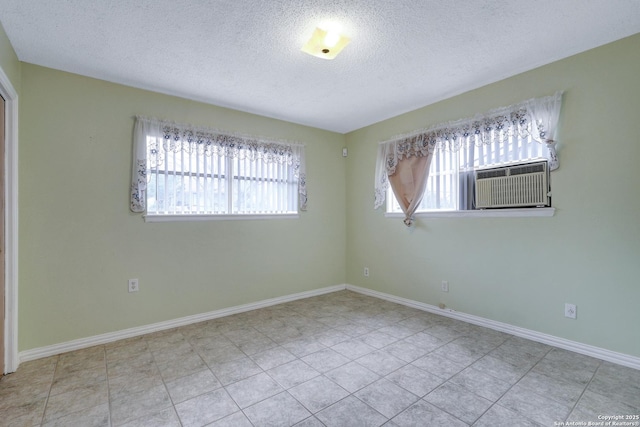 spare room with a textured ceiling, baseboards, and light tile patterned floors