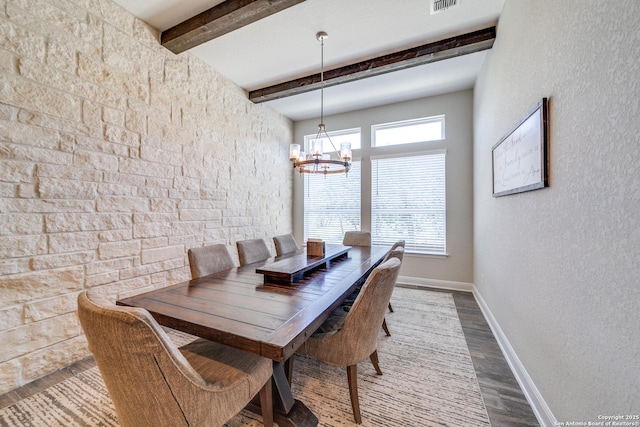 dining room with baseboards, visible vents, wood finished floors, a chandelier, and beam ceiling