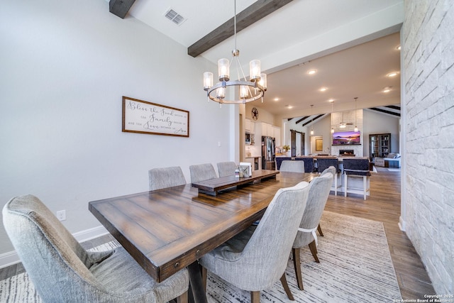 dining area featuring recessed lighting, visible vents, lofted ceiling with beams, wood finished floors, and a chandelier