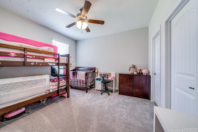 bedroom with a ceiling fan, light carpet, and a textured ceiling