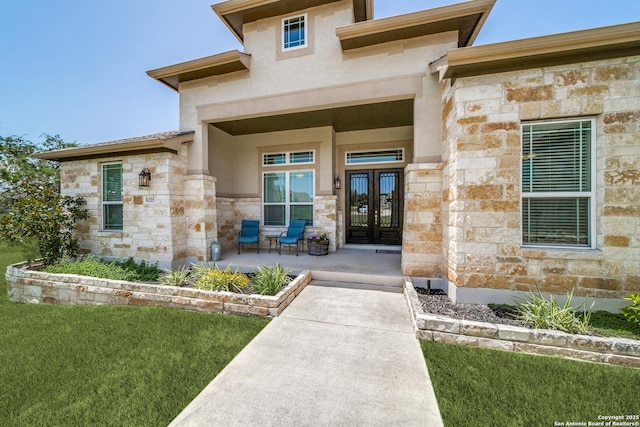 doorway to property with stone siding, french doors, a lawn, and stucco siding