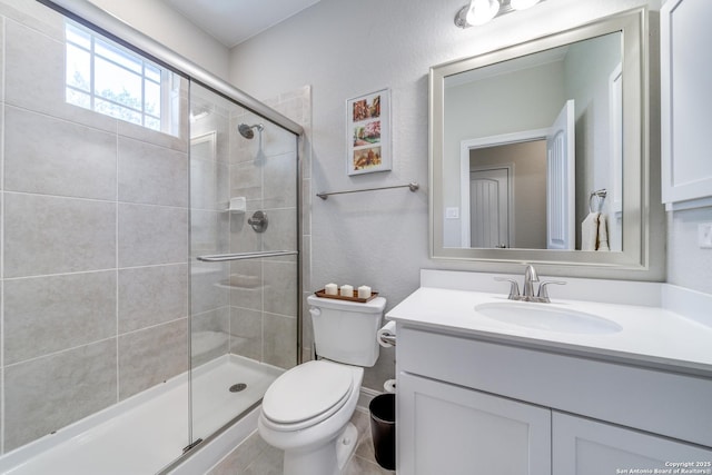 bathroom featuring vanity, a shower stall, and toilet