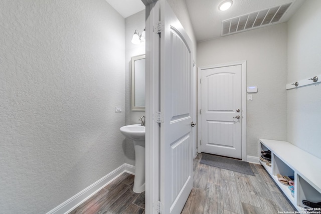 bathroom featuring a textured wall, wood finished floors, visible vents, and baseboards