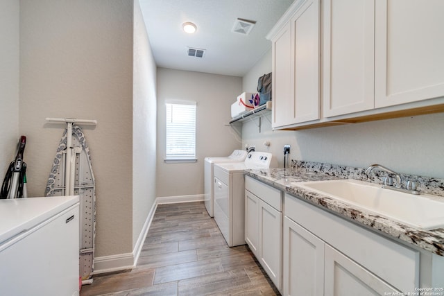 washroom featuring washer and dryer, visible vents, a sink, and cabinet space