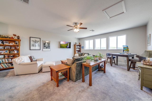 living room with light carpet, attic access, visible vents, and ceiling fan