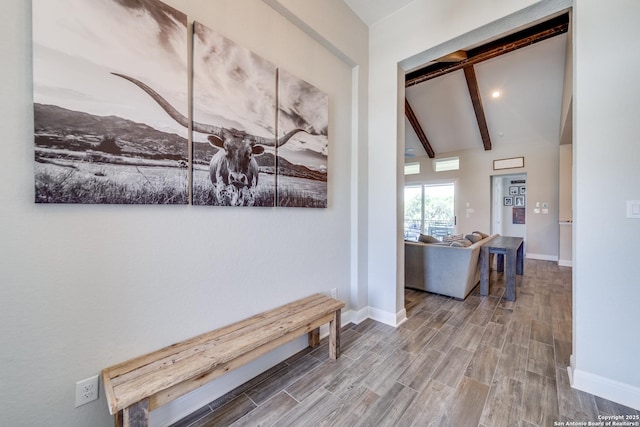 corridor featuring lofted ceiling with beams, baseboards, and wood finished floors