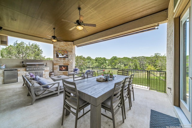 view of patio featuring a ceiling fan, area for grilling, outdoor dining area, exterior kitchen, and an outdoor stone fireplace