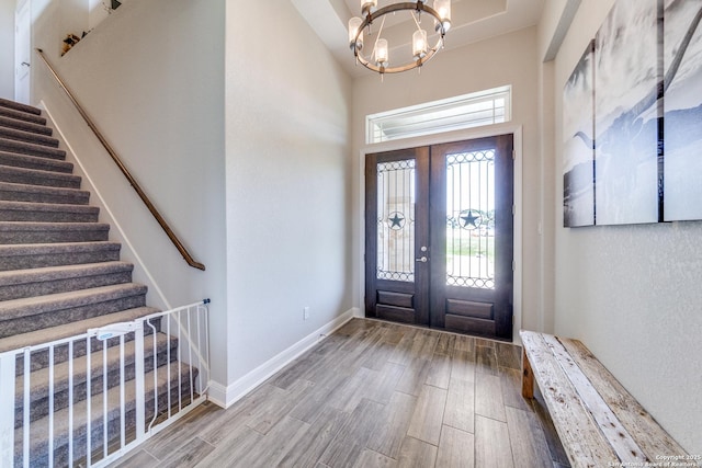 foyer featuring stairs, baseboards, an inviting chandelier, and wood finished floors