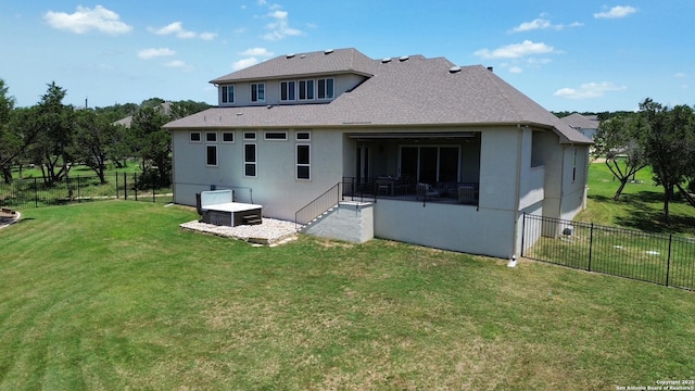 back of house with a fenced backyard, a lawn, and stucco siding