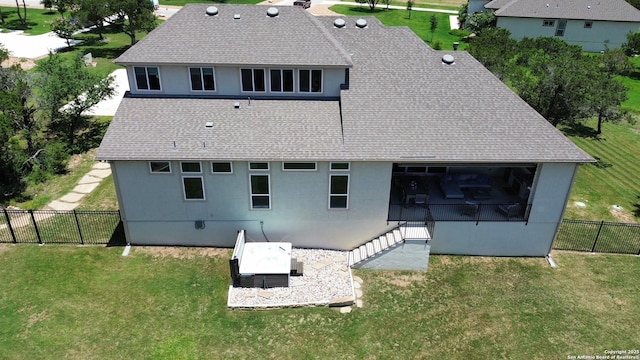 rear view of property featuring a patio, a shingled roof, a lawn, and fence