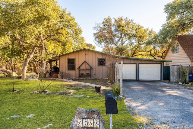 view of front facade with aphalt driveway, board and batten siding, an attached garage, and a front yard