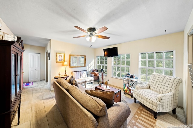 living room with a textured ceiling, baseboards, and a ceiling fan