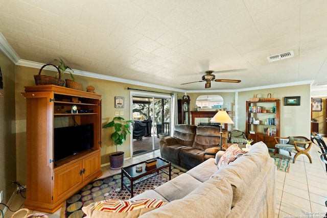 living area with light tile patterned floors, a ceiling fan, visible vents, and crown molding