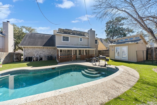 back of property with brick siding, an outdoor structure, fence, a lawn, and a patio area