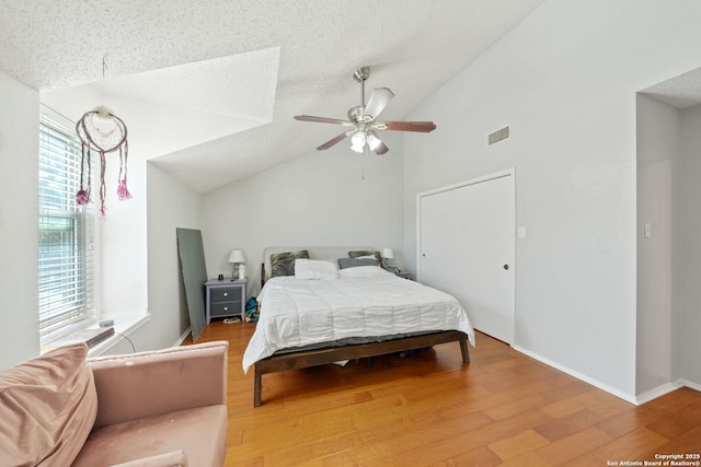 bedroom featuring lofted ceiling, a textured ceiling, baseboards, and wood finished floors