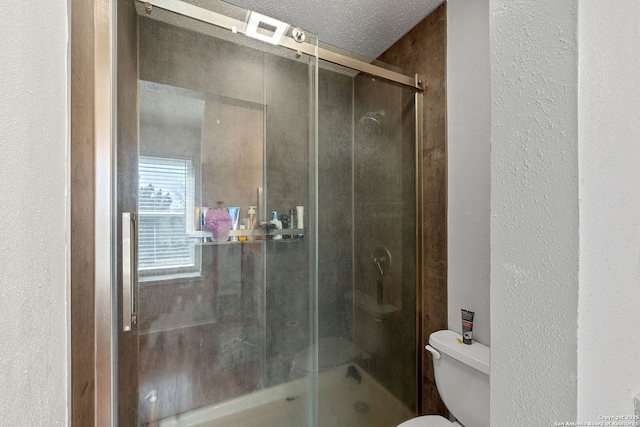 full bath featuring toilet, a stall shower, a textured ceiling, and a textured wall