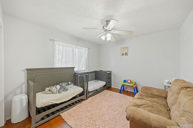 bedroom featuring ceiling fan, a textured ceiling, baseboards, and wood finished floors