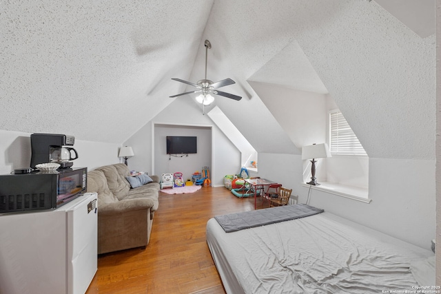 bedroom featuring a textured ceiling, vaulted ceiling, wood finished floors, and a ceiling fan