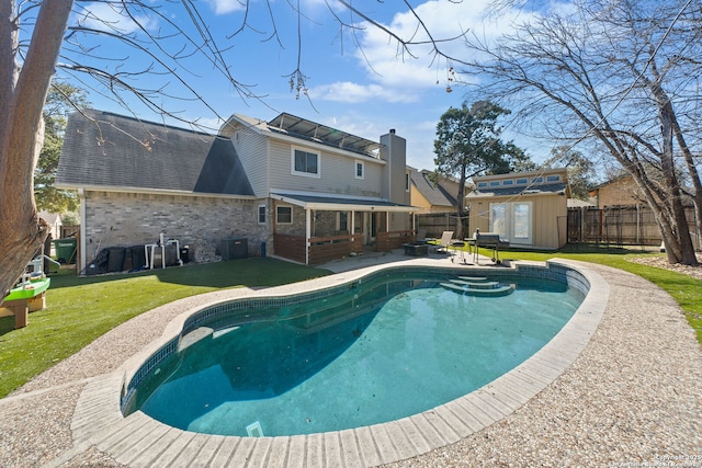 view of swimming pool with a fenced in pool, an outbuilding, a lawn, a shed, and a fenced backyard