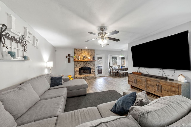 living area featuring a brick fireplace, wood finished floors, and a ceiling fan