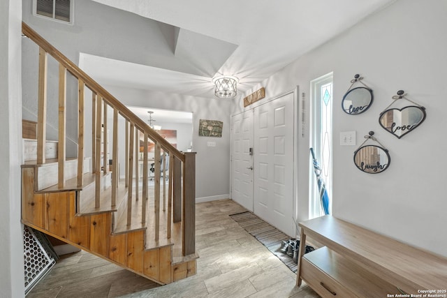 foyer with light wood-style flooring, stairs, visible vents, and a notable chandelier