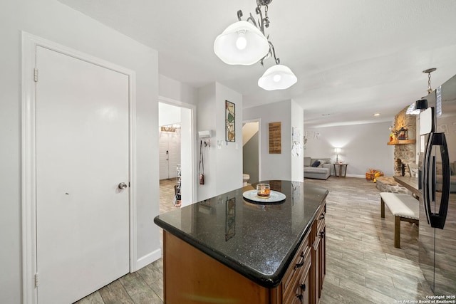 kitchen with pendant lighting, brown cabinets, freestanding refrigerator, a kitchen island, and light wood-type flooring