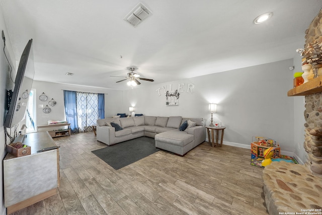 living area with a ceiling fan, baseboards, visible vents, and wood finished floors