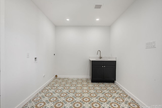 washroom featuring visible vents, a sink, cabinet space, and baseboards