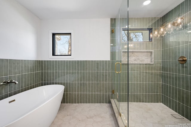 full bath with tile walls, a soaking tub, and a shower stall