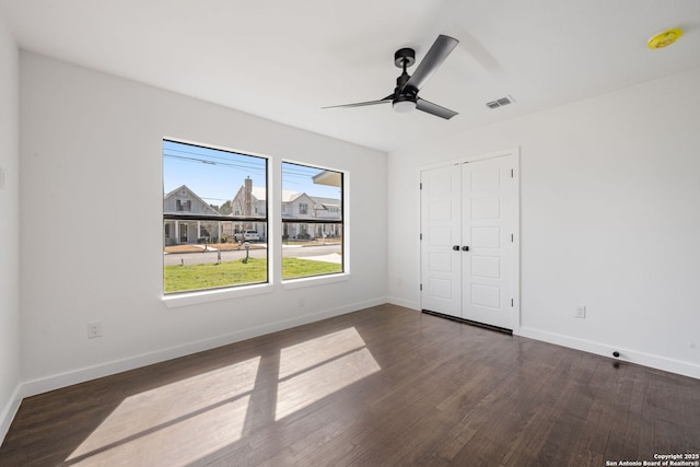 unfurnished bedroom featuring baseboards, a closet, visible vents, and dark wood-style flooring