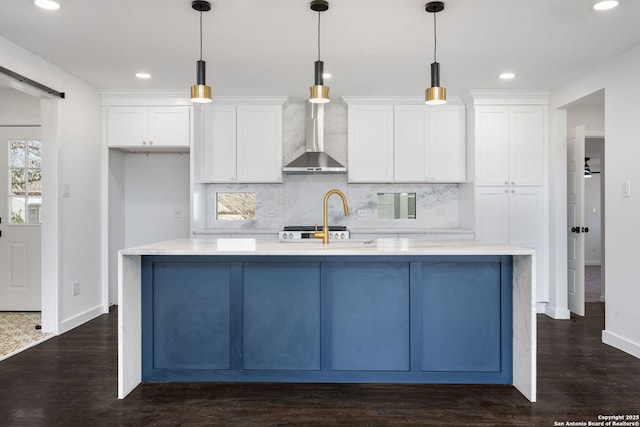 kitchen featuring light countertops, a center island with sink, decorative light fixtures, and a barn door