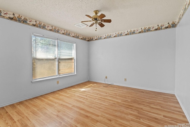 spare room with a textured ceiling, ceiling fan, light wood-style flooring, visible vents, and baseboards