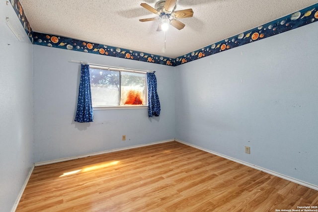 unfurnished room with a textured ceiling, wood finished floors, a ceiling fan, and baseboards