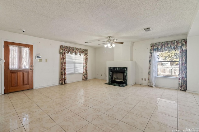 unfurnished living room with light tile patterned floors, a premium fireplace, visible vents, and a ceiling fan