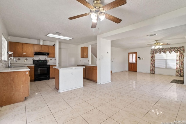 kitchen with a sink, a center island, light countertops, brown cabinets, and black electric range oven