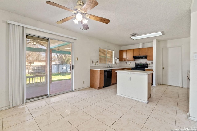 kitchen featuring brown cabinetry, a center island, light countertops, black appliances, and a sink