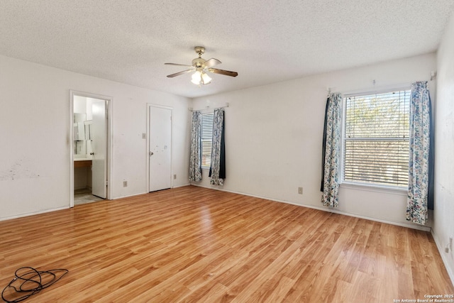 empty room featuring light wood-style floors, a textured ceiling, and a ceiling fan