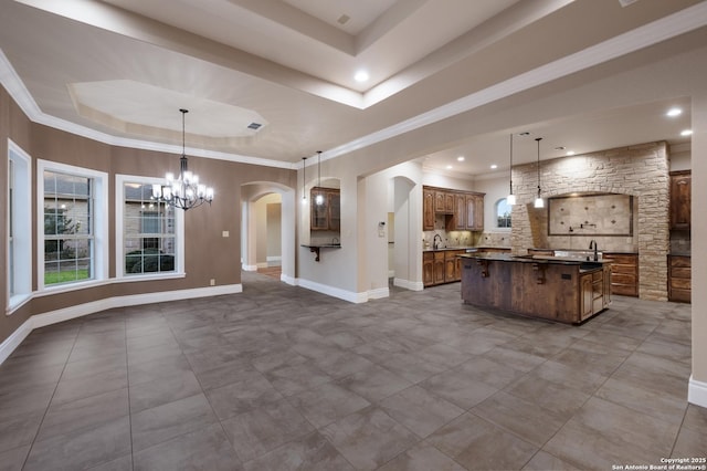 kitchen featuring hanging light fixtures, dark countertops, a tray ceiling, and brown cabinets