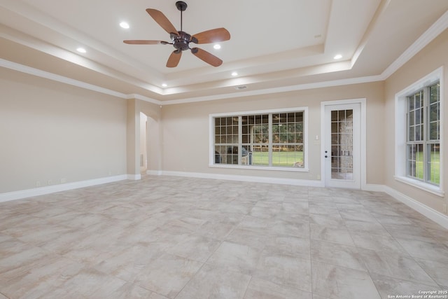 unfurnished room with ornamental molding, a tray ceiling, recessed lighting, and baseboards