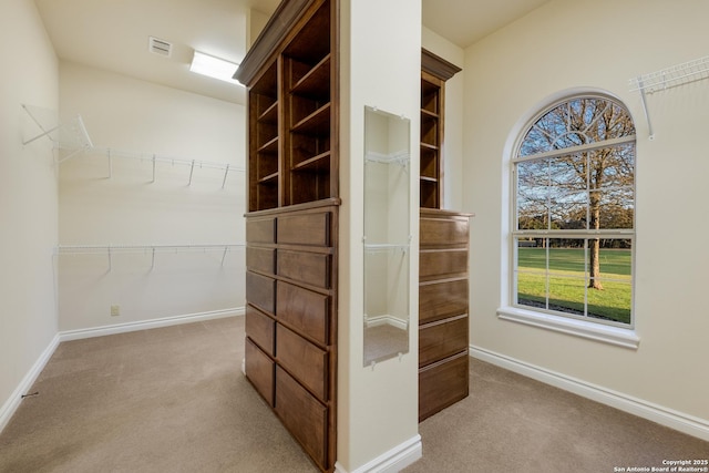 walk in closet with visible vents and light colored carpet