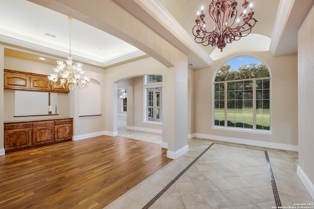 entryway featuring ornamental molding, light wood-type flooring, a raised ceiling, and baseboards