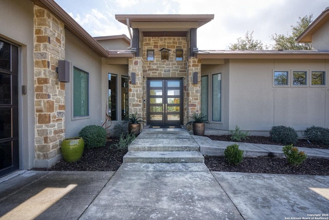 property entrance featuring stone siding, french doors, and stucco siding