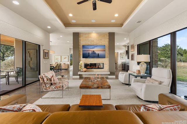 living room with a tray ceiling, visible vents, a multi sided fireplace, and recessed lighting