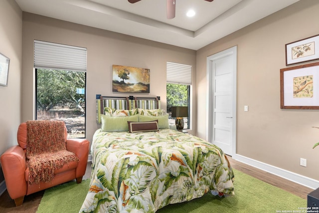 bedroom with recessed lighting, a raised ceiling, ceiling fan, wood finished floors, and baseboards