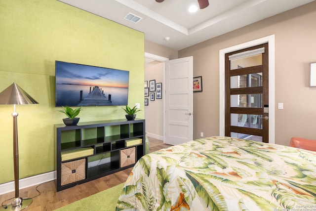 bedroom featuring recessed lighting, a raised ceiling, visible vents, wood finished floors, and baseboards