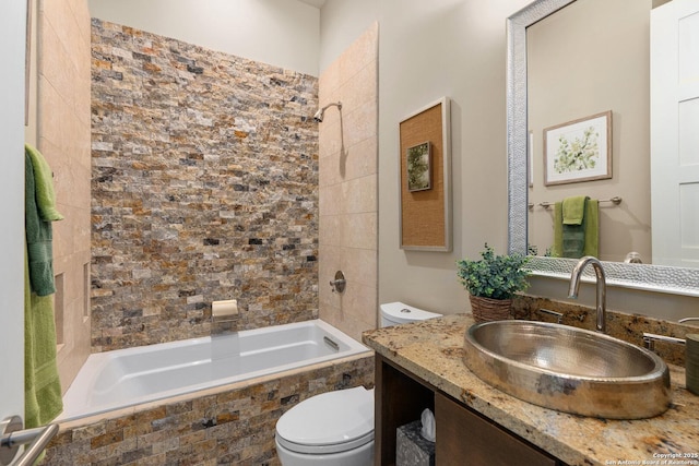 full bathroom featuring tiled shower / bath, vanity, and toilet