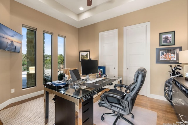 office area featuring ceiling fan, recessed lighting, baseboards, light wood-style floors, and a raised ceiling