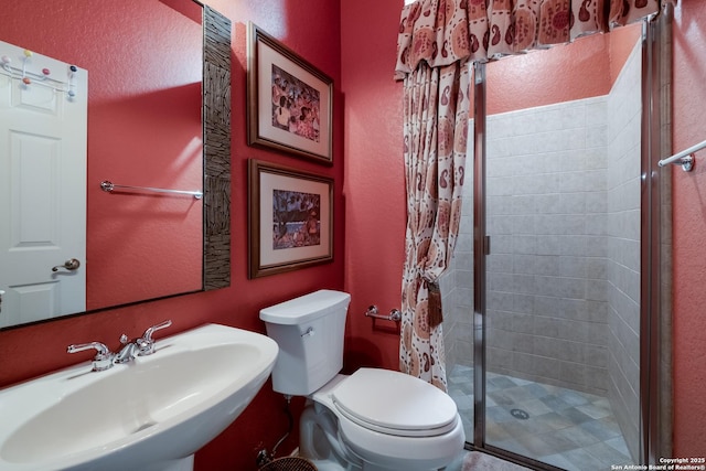 full bath with a textured wall, a sink, toilet, and a shower stall