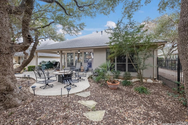 back of house with ceiling fan, a fire pit, a shingled roof, fence, and a patio area